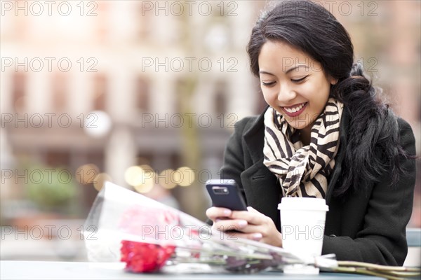 Mixed race woman text messaging on cell phone