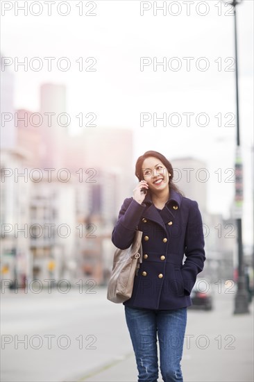 Mixed race woman walking and talking on cell phone