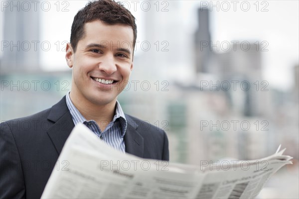 Mixed race businessman reading newspaper