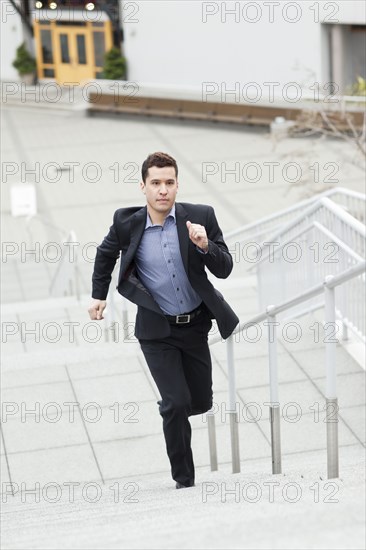 Mixed race businessman running up stairs