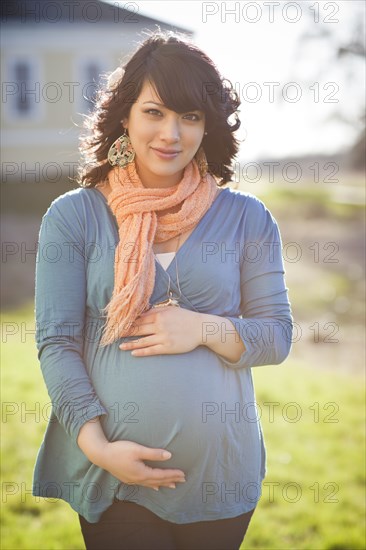 Pregnant mixed race woman holding stomach