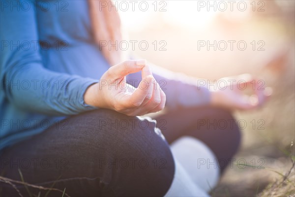 Pregnant mixed race woman practicing yoga in field