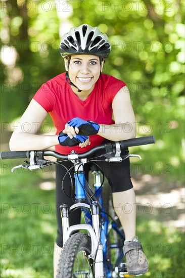 Hispanic woman riding mountain bike in forest