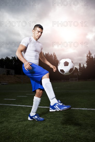 Hispanic athlete kicking soccer ball