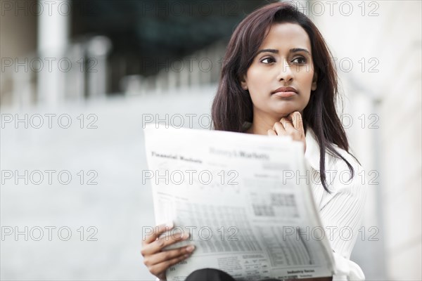 Indian businesswoman reading newspaper outdoors