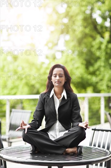 Indian businesswoman practicing yoga on tabletop