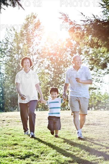 Chinese grandparents holding hands with grandson