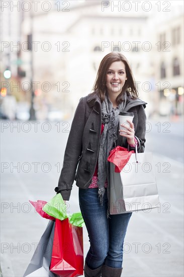 Mixed race woman shopping and drinking coffee