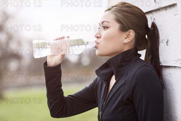 Asian woman drinking bottle of water