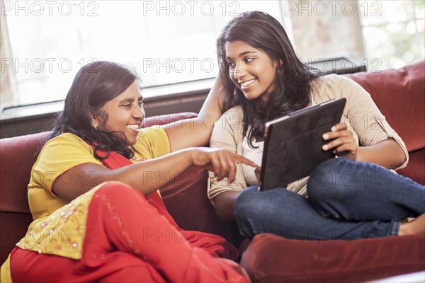 Indian mother and daughter using digital tablet