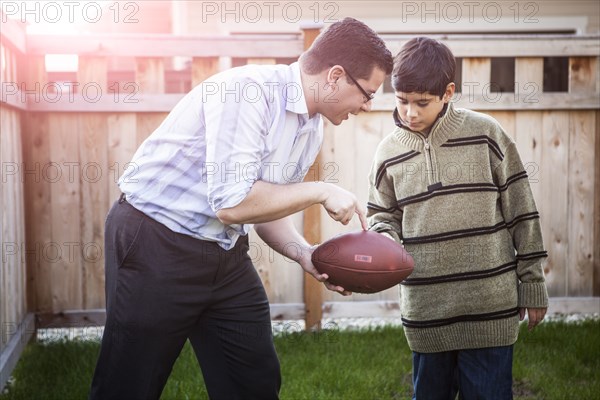 Hispanic father teaching son to play football