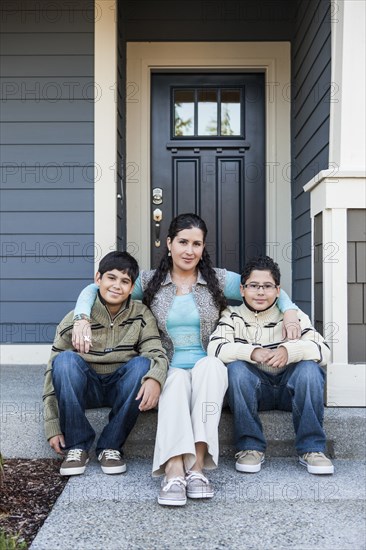 Hispanic mother and sons sitting on front stoop