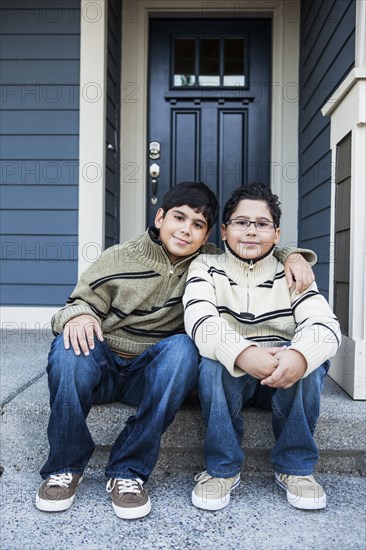 Hispanic boys hugging on front stoop