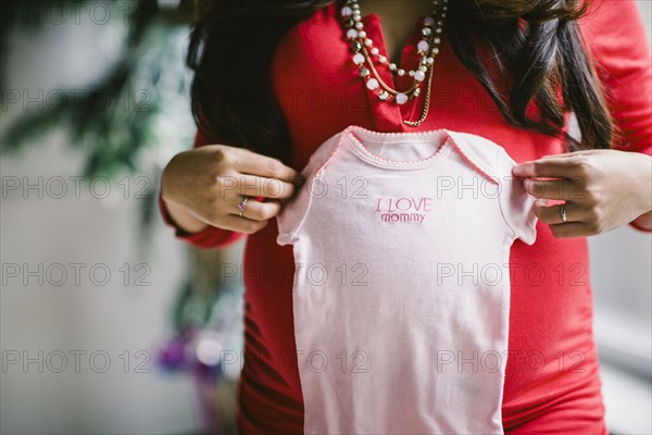 Pregnant Asian woman holding baby clothes