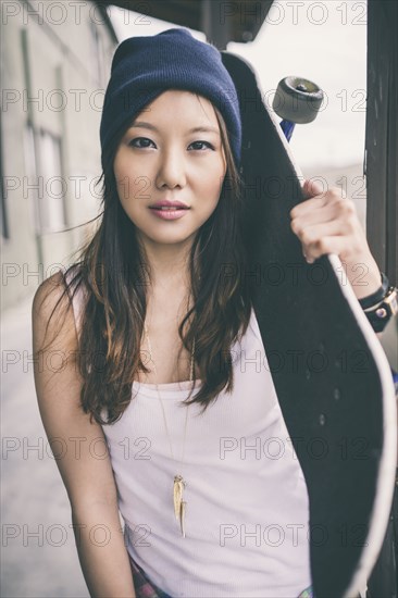 Korean woman carrying skateboard on city street