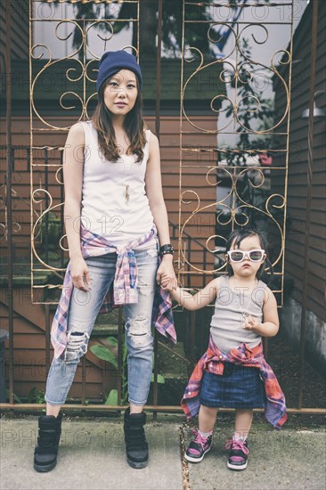 Korean mother and daughter holding hands on city street