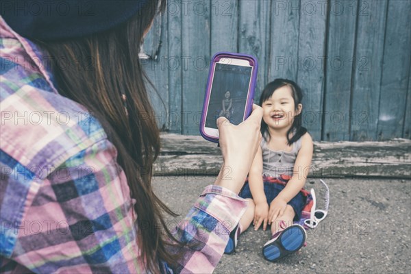 Korean mother taking pictures of daughter on city street