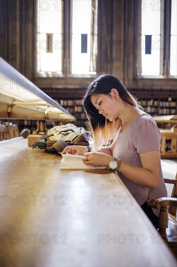 Chinese woman sitting in library reading book