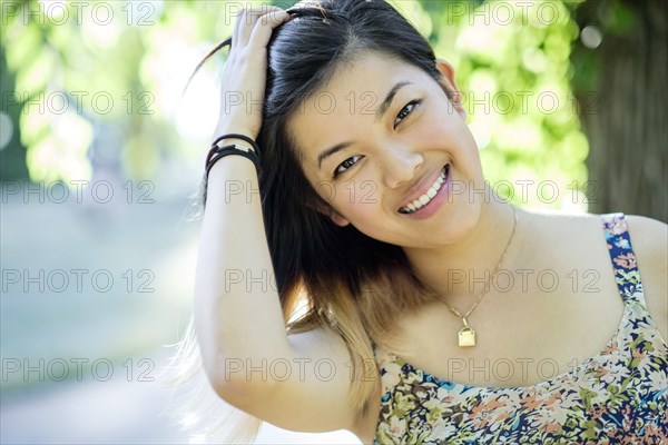 Portrait of smiling Chinese woman with hand in hair