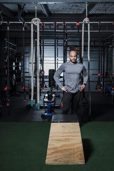 Mixed Race man looking at wooden platform in gymnasium