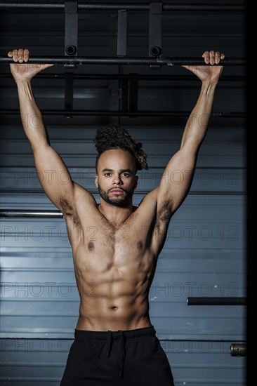 Mixed Race man holding bar in gymnasium