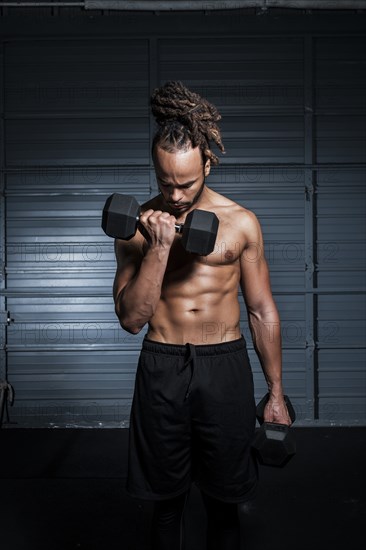 Mixed Race man lifting weights in gymnasium