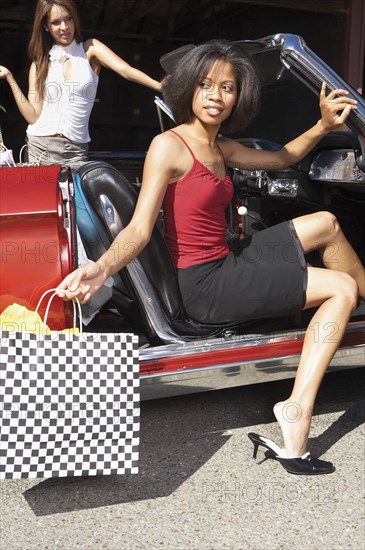 Two women getting out of convertible after shopping