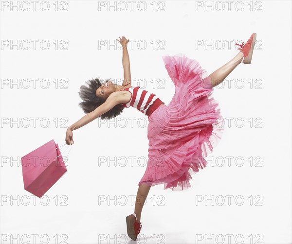 Full view portrait of woman in skirt dancing with leg and arms in air