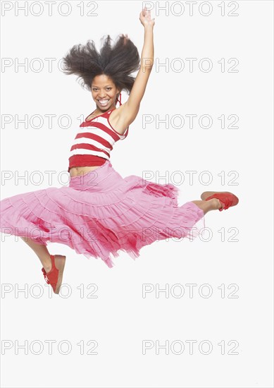 Full view portrait of woman in skirt jumping up