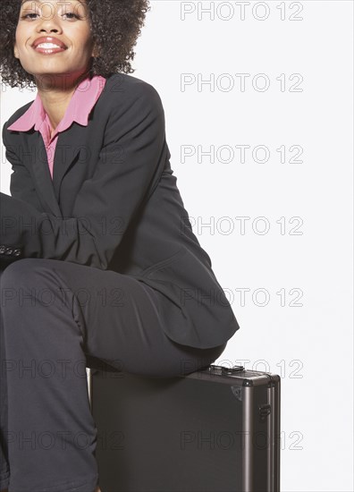 Businesswoman sitting on metal briefcase