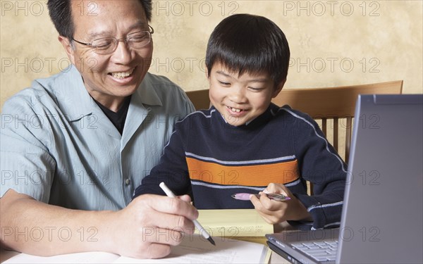 Asian father helping young son with homework