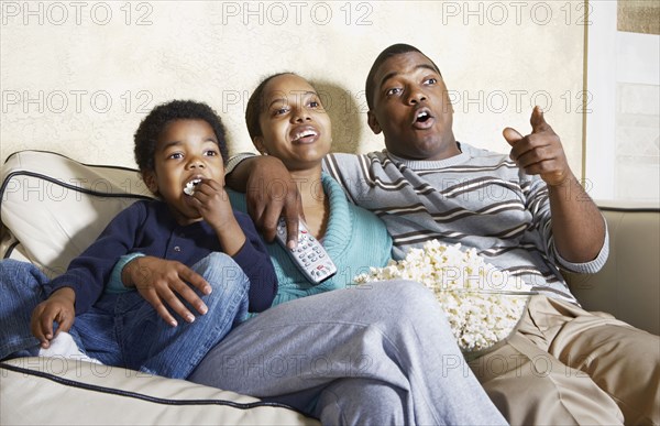 African American family watching television with popcorn