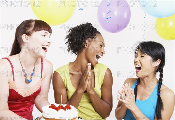 Three women laughing with cake at party