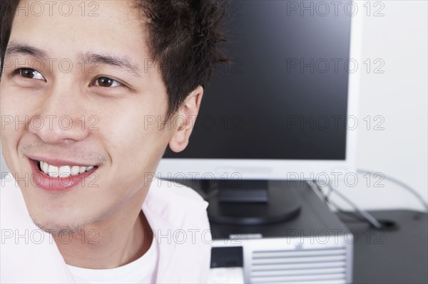 Close up of young Asian man next to computer