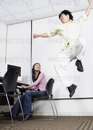 Asian man jumping next to Asian female computer service technician