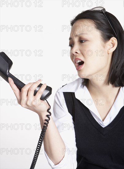 Studio shot of Asian businesswoman yelling at telephone