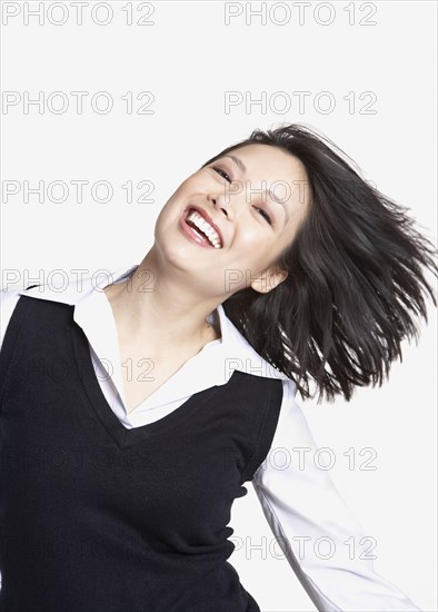 Studio shot of Asian woman tossing hair and smiling