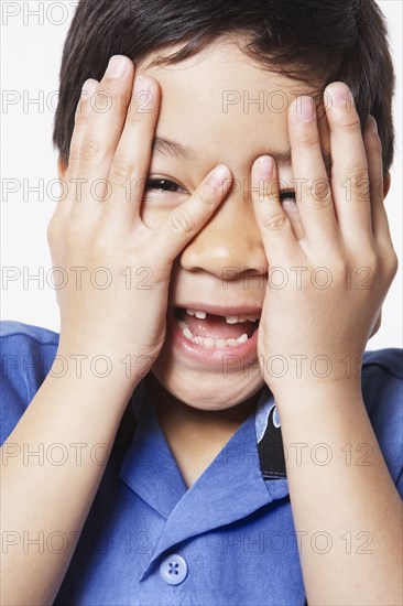 Young boy covering face with hands