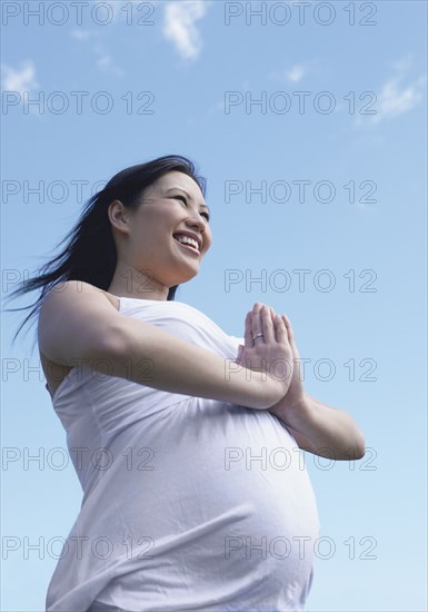 Pregnant Asian woman doing yoga outdoors