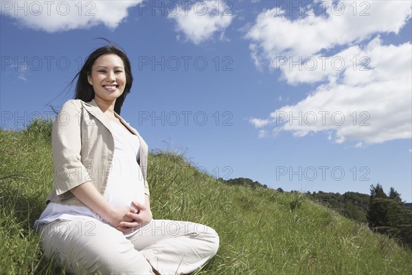 Pregnant Asian woman sitting outdoors