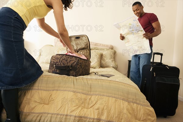 African couple packing suitcase on bed