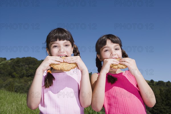 Young Hispanic sisters eating cookies outdoors