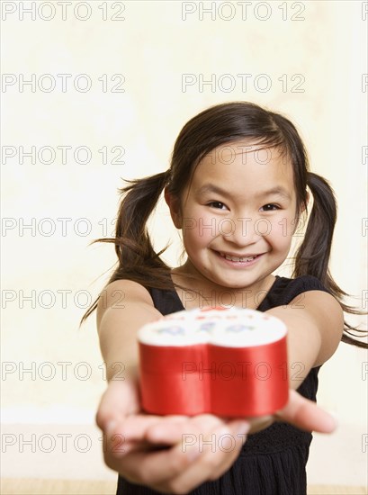 Young Asian girl with heart box in outstretched hands