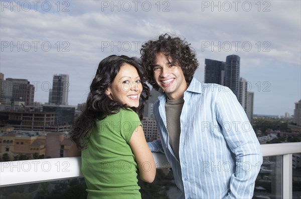 Hispanic couple leaning against balcony railing