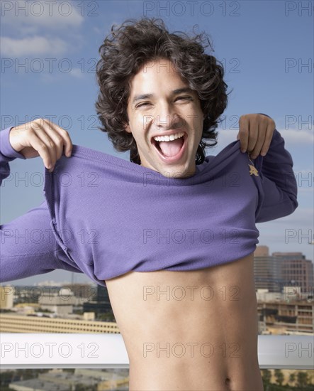 Hispanic man pulling up shirt