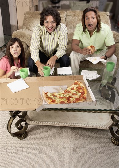Multi-ethnic friends watching television and eating