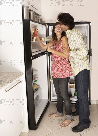 Hispanic couple looking in refrigerator