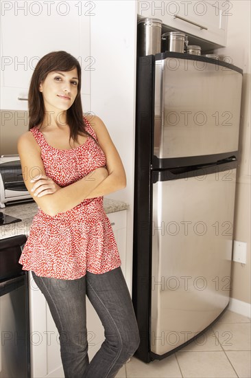 Hispanic woman with arms crossed in kitchen