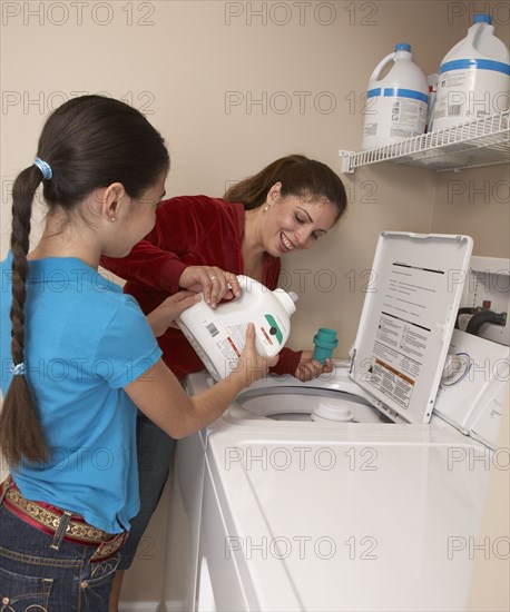 Hispanic mother and daughter doing laundry