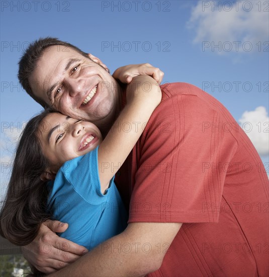 Hispanic father and daughter hugging